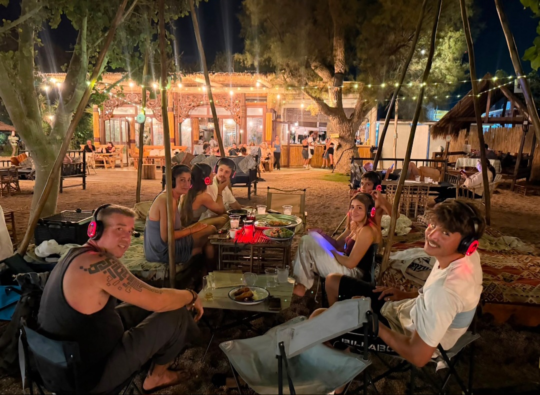 קבוצה יושבת עם אוזניות ורודות מתחת לאורות בגן
